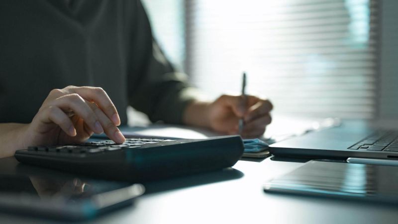 Person analyzing law firm cash flow with laptop and calculator