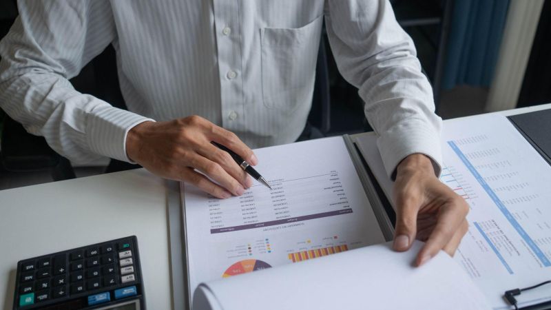a man in a white shirt is holding a pen and paper