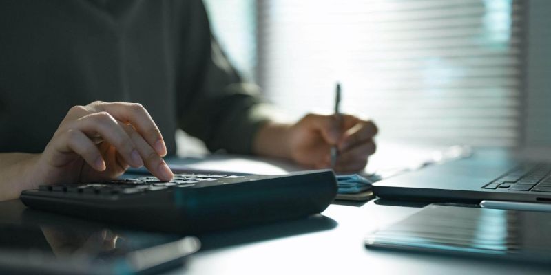 Person analyzing law firm cash flow with laptop and calculator