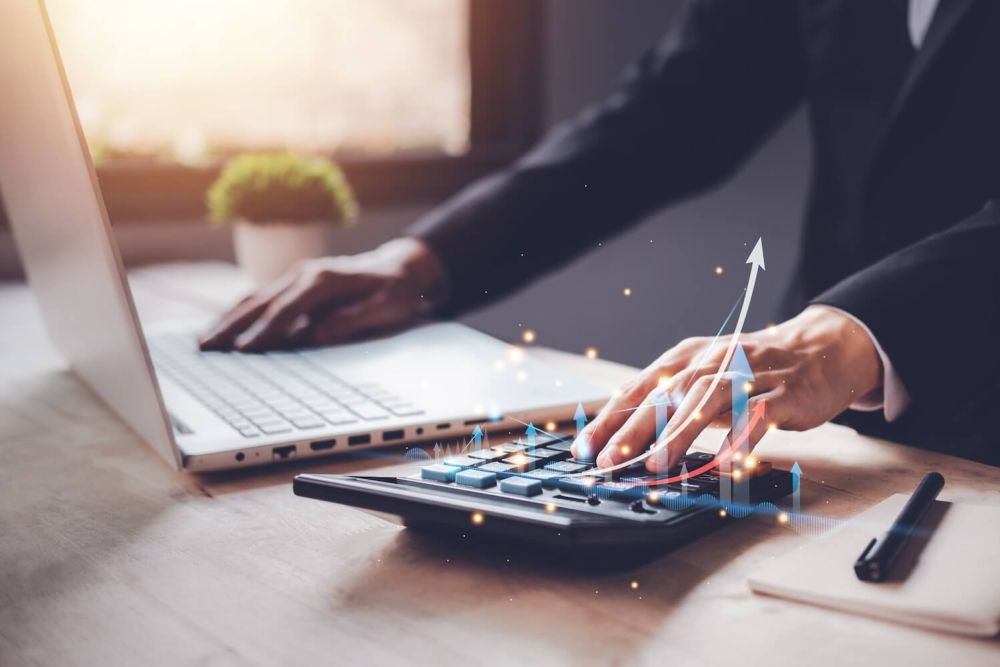 man at desk using calculator Maximizing Profits