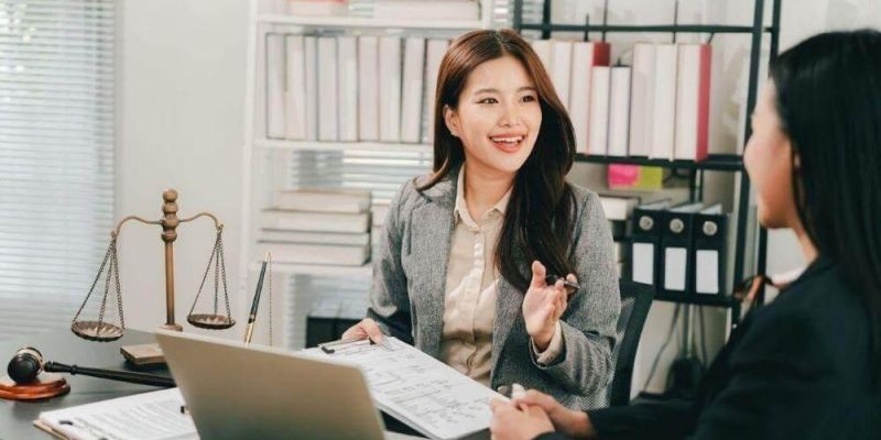 a woman sitting at a desk talking to another woman
