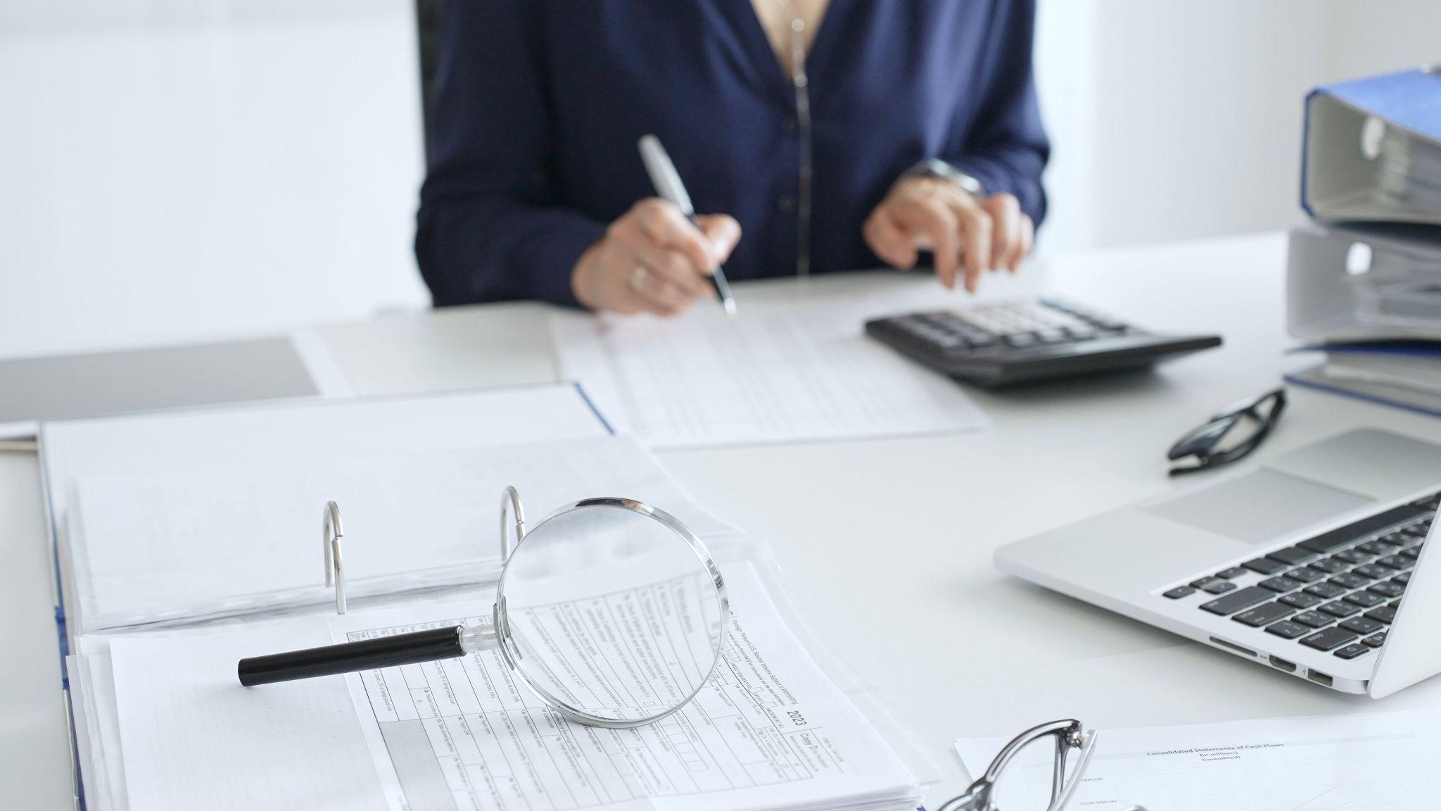 a woman sitting at a desk with a calculator and a laptop