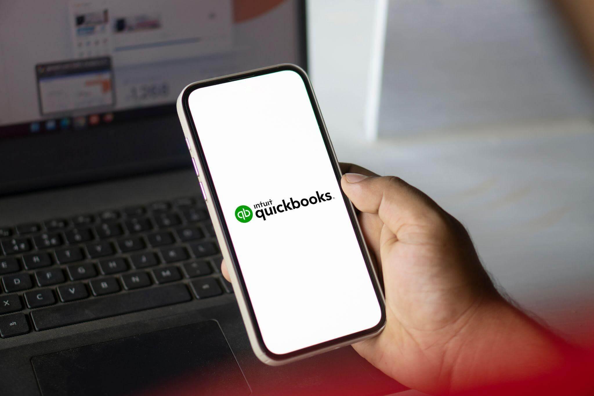 a person holding a cell phone in front of a laptop