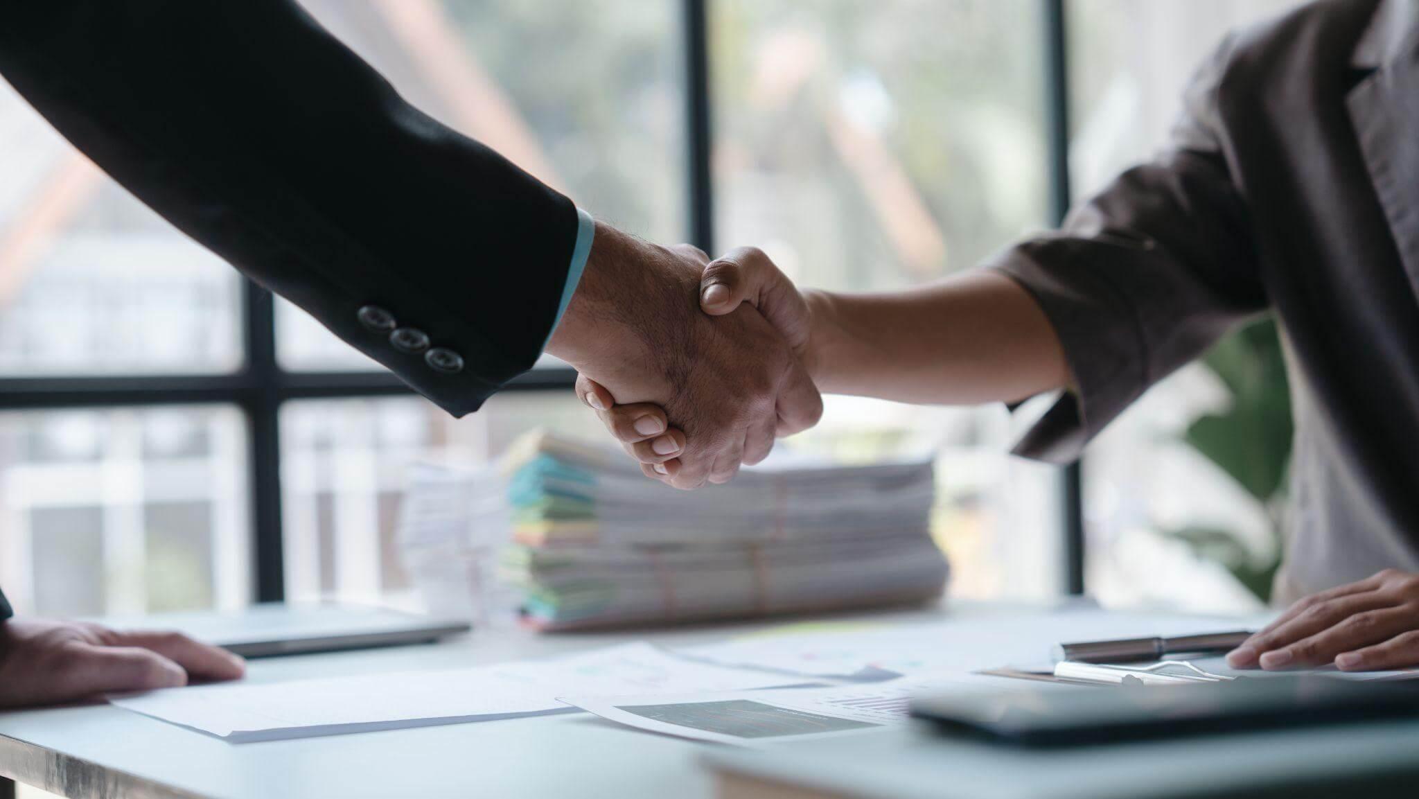 Clients shaking hands over a table after a diagnostic review