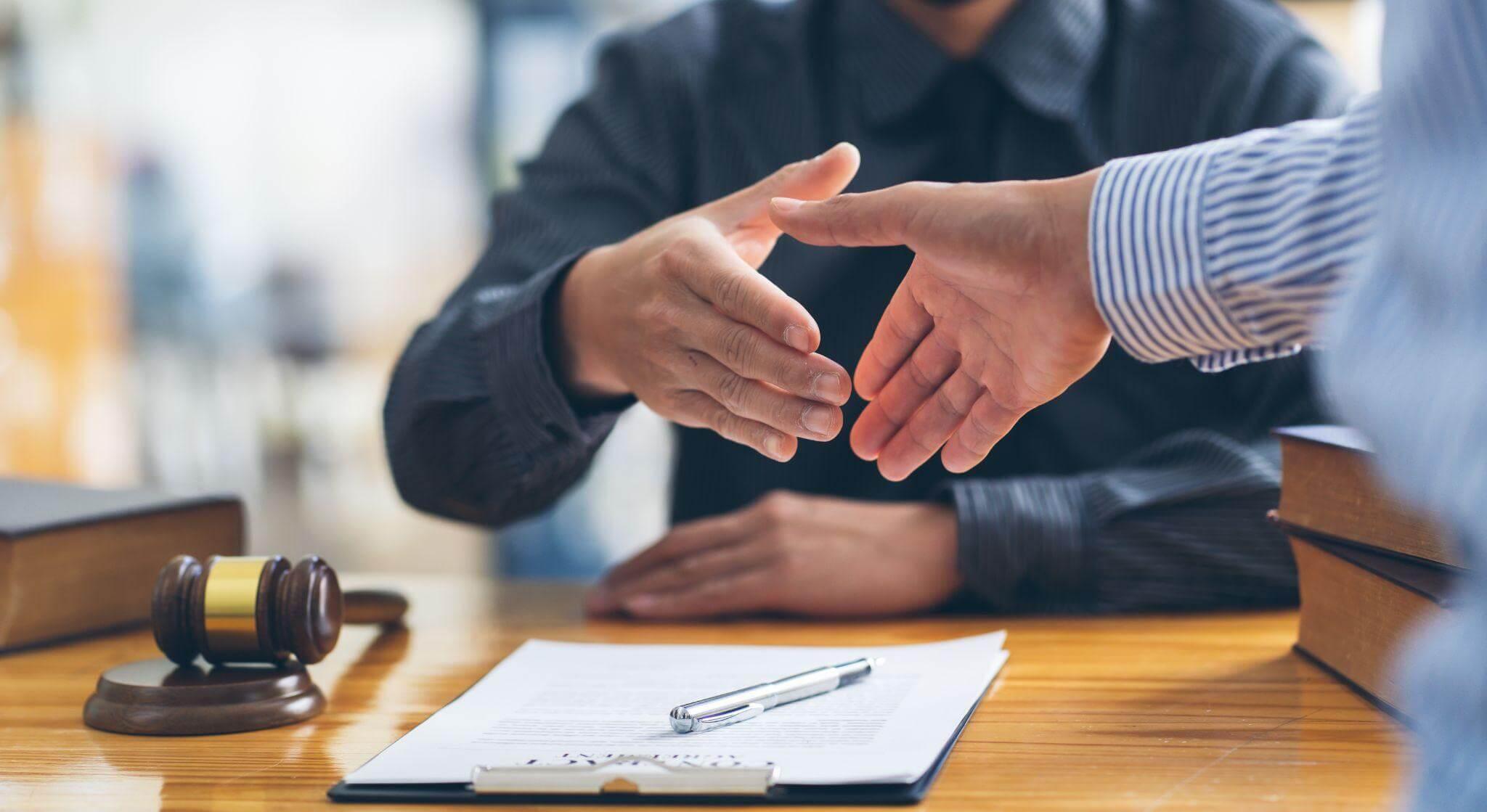 Two people shaking hands at a table, possibly